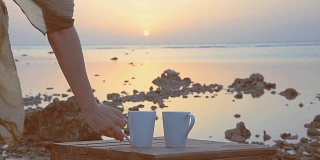 一个女孩在大海的背景上喝着咖啡