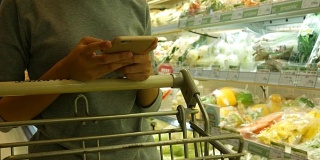 在超市用智能手机的女人