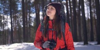 微笑快乐的年轻女子徒步在冬天的森林使用相机拍照。