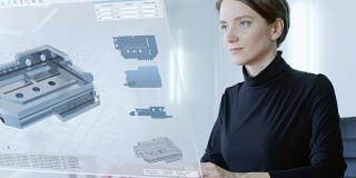 在不久的将来美丽的女工程师工作在她的电脑透明显示。她构建了复杂的三维模型。办公室是明亮和现代的。