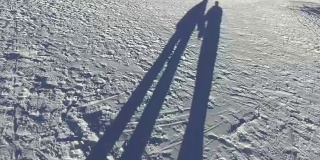 浪漫的情侣手牵着手走在雪地上的影子