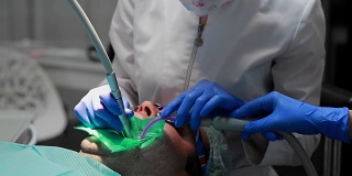 牙医和护士正在给一个病人补牙。用bormashenko钻牙，清除蛀牙和密封