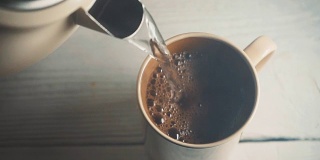 用水壶里的热水把咖啡倒进陶瓷杯里