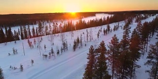 镜头:冬日金色的日出下，汽车行驶在雪地里的乡村道路上