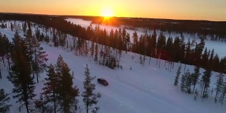 图片:人们在冬季自驾游，在日落时分在冰雪覆盖的拉普兰荒野中旅行