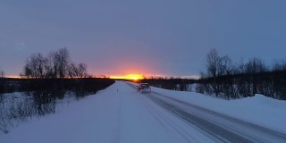 在拉普兰滑冻的道路上，一辆空中汽车驶入金色的冬日日出