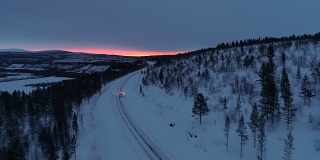 摄影:日出时分，汽车行驶在雪山公路上穿过松林