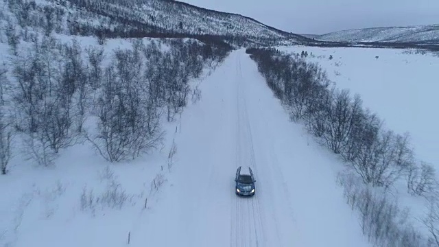 空中特写:汽车在芬兰冬季山谷的冰雪道路上行驶