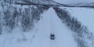 空中特写:汽车在芬兰冬季山谷的冰雪道路上行驶