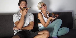 一对夫妇在电视旁吃披萨