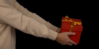 身穿米色毛衣的成年白人男子手中的红色礼品盒。近距离锁定。庆典前夕。事件圣诞节新年感恩节黑色星期五生日母亲父亲情人节。