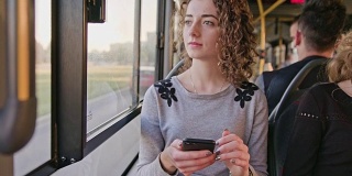 一位年轻女士在公交车上使用智能手机