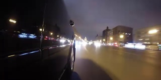 快速城市驾驶夜间道路POV通过城市在夜间时间推移左侧的汽车。低角度的观点。相机拍摄回来