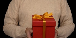 一名身穿米色毛衣的白人男子手里拿着一个礼品盒。正面的男人在休闲米色毛衣。人类给了礼物。Alpha通道色度键透明背景。锁定。