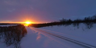 夕阳下，半挂车行驶在积雪覆盖的公路上