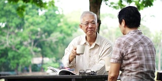 亚洲老年夫妇在美丽的公园早上喝咖啡