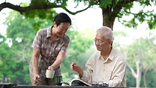 亚洲老年夫妇在美丽的公园早上喝咖啡视频素材模板下载