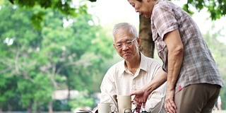 亚洲老年夫妇在美丽的公园早上喝咖啡