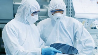 两名工程师/科学家/技术员穿着无菌服检查半导体硅片。他们在一家现代半导体制造厂工作。视频素材模板下载