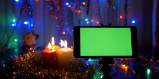 新年的背景，在前景有一个绿色屏幕的智能手机。一个很好的机会添加您的问候视频。