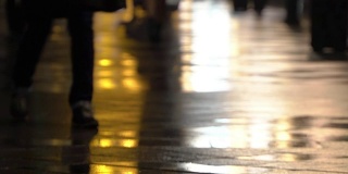 在潮湿的人行道上，街灯映出了辨认不出的人的剪影。长长的影子。雨夜的城市街道上有路灯，沥青路从雨中闪闪发光。不认识的行人，年轻人。夜晚的城市下雨。购物的概念