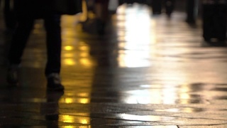 在潮湿的人行道上，街灯映出了辨认不出的人的剪影。长长的影子。雨夜的城市街道上有路灯，沥青路从雨中闪闪发光。不认识的行人，年轻人。夜晚的城市下雨。购物的概念视频素材模板下载