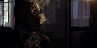 一个抽着雪茄，烟瘾很大的剪影男人