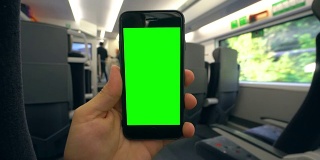 在火车上拿着绿色屏幕的手机