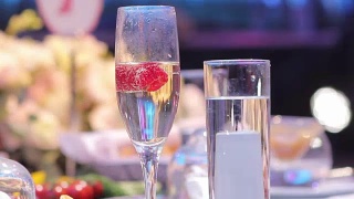 在自助餐桌上，在餐厅或酒店大堂的自助餐桌上，配有香槟和水果的玻璃杯，镜头沿着，景深浅，在餐厅大堂欢迎客人视频素材模板下载