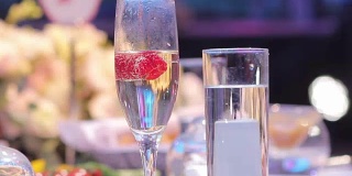 在自助餐桌上，在餐厅或酒店大堂的自助餐桌上，配有香槟和水果的玻璃杯，镜头沿着，景深浅，在餐厅大堂欢迎客人