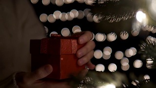 女人打开红色的圣诞礼盒上的散景灯背景视频素材模板下载
