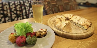 一个年轻的女孩拿着一块传统的格鲁吉亚哈切布里菜和肉。多色什锦菜，格鲁吉亚菜，搭配坚果和库布达里