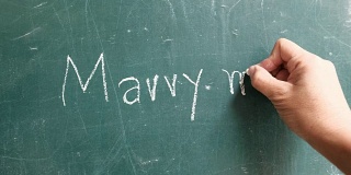 男人用粉笔在黑板上写着“嫁给我”。