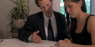 困惑的女人和一个穿西装打领带的男人签署文件