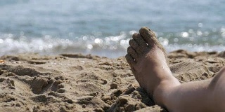 躺在海边沙滩上的女人的腿