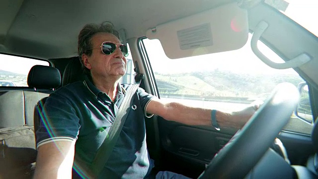 退休老人在高速公路上开车。老男人握着方向盘，表情坚定，表情丰富，他的脸在4K