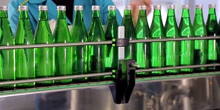 生产线上的一名员工擦拭绿色的矿泉水玻璃瓶