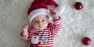可爱的新生小男婴圣诞肖像，穿着圣诞服装，戴着圣诞帽，工作室拍摄，冬天的时候