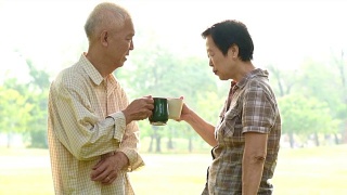 亚洲老夫妇在公园喝咖啡庆祝生活视频素材模板下载