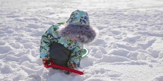 一个小孩在冬天的公园里玩雪。阳光明媚的冬日。新鲜的空气里充满了乐趣和游戏。