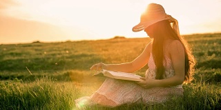 女孩在日落时读着关于乡村风景的书
