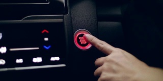 特写的女性手指推动汽车启动-停止灯按钮上的一辆汽车的仪表盘