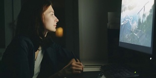 专注的年轻女性设计师晚上在办公室使用电脑和图形板完成工作