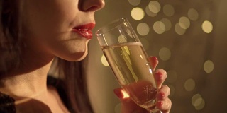美丽的女人在圣诞花环灯下喝香槟