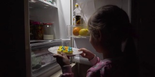 小女孩从冰箱里拿出饼干。