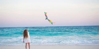 日落时分，小女孩在热带海滩上放风筝。孩子们在海边玩耍。有沙滩玩具的孩子。