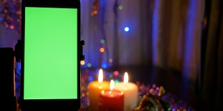 绿色屏幕的智能手机。新年的灯光模糊了背景。