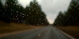 冒着雨在高速公路上开车。透过被雨滴覆盖的挡风玻璃