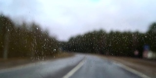 冒着雨在高速公路上开车。透过被雨滴覆盖的挡风玻璃
