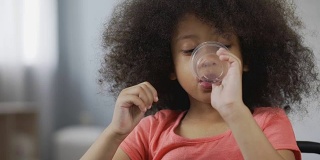 口渴的美国黑人孩子喝着矿泉水，这是孩子脸的特写